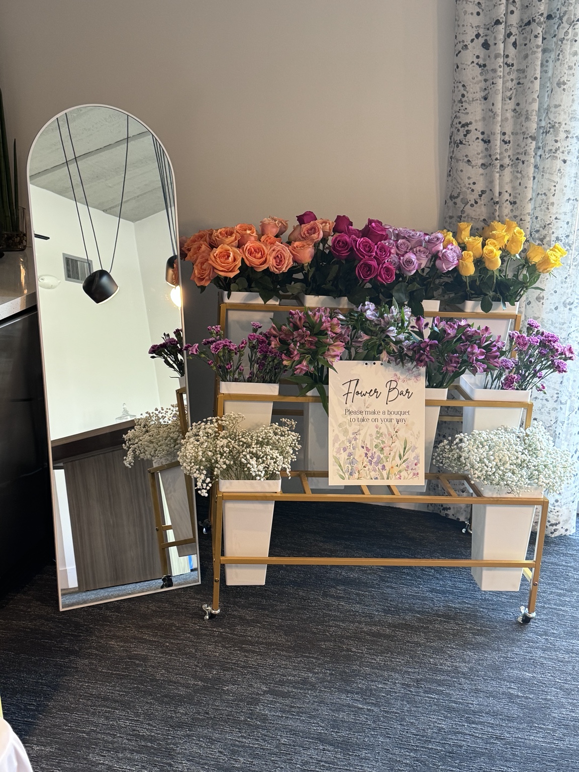 Adorn Designs flower bar with colorful roses and a gold display cart beside a tall mirror