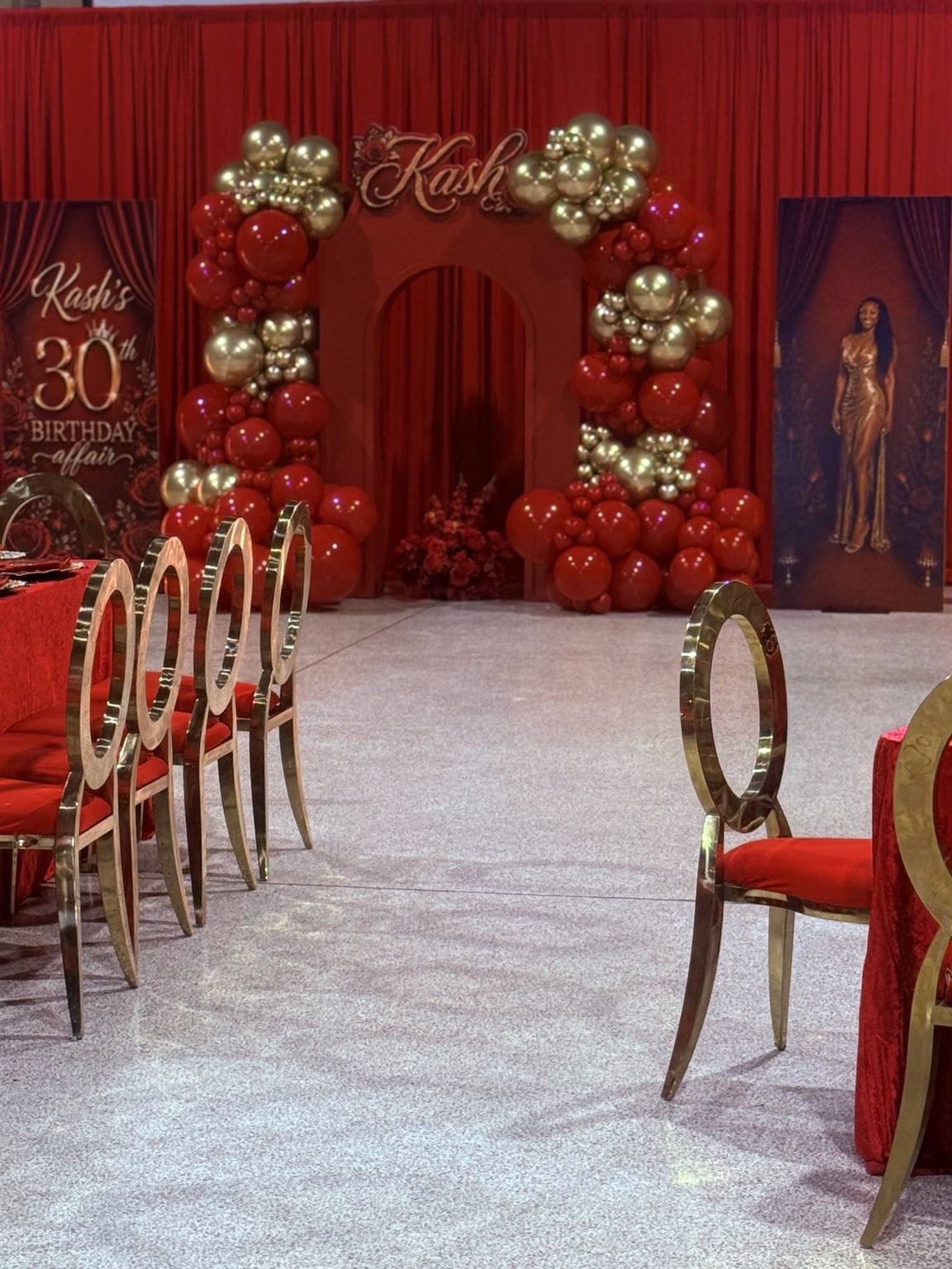 Red and gold balloon installation framing an arch at a 30th birthday celebration